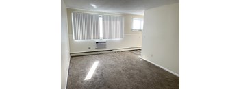 A room with a window covered by blinds and a small air conditioning unit on the wall.