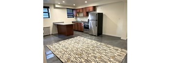 A kitchen with a black refrigerator and brown cabinets.