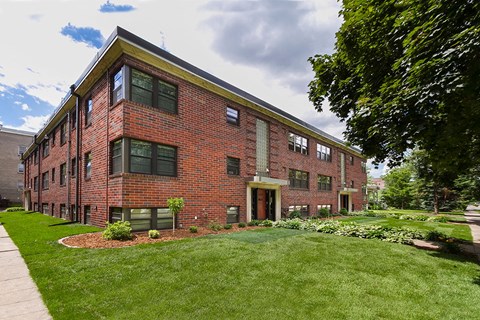 A red brick building with a green lawn in front.