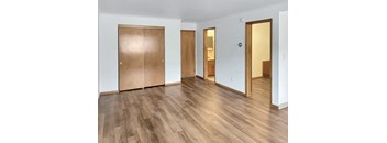 A room with wooden floors and three wooden doors.