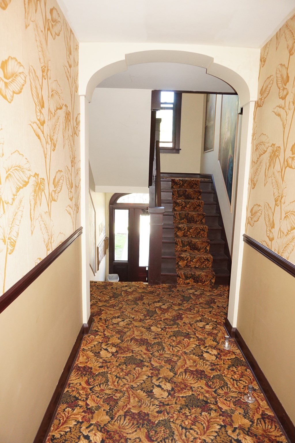 A hallway with a carpeted floor and a staircase.