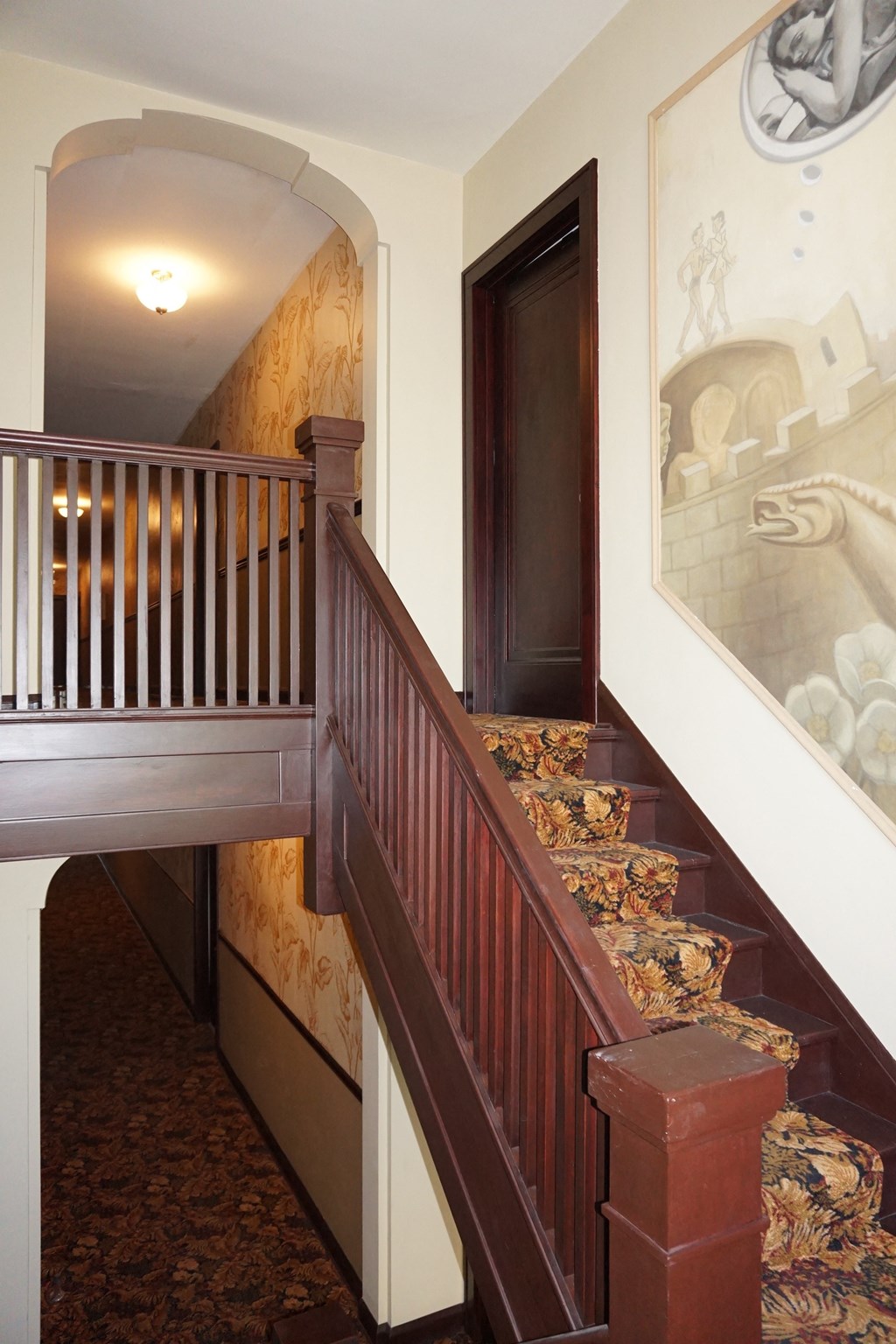 A staircase with a wooden handrail and a patterned carpet.