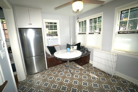 A kitchen with a refrigerator and a dining table with chairs.