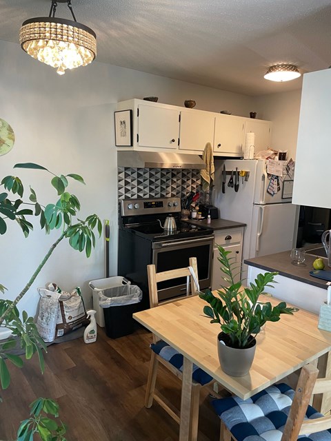 A kitchen with a table and chairs in the foreground and a refrigerator in the background.