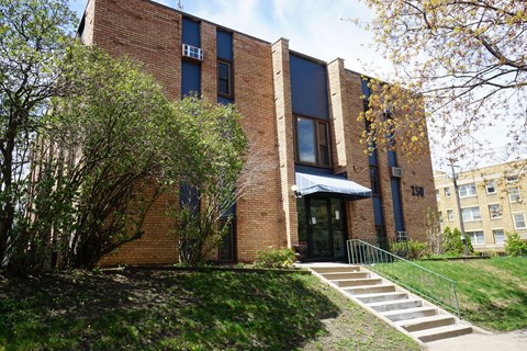 A red brick building with a black awning and a set of stairs leading up to the entrance.