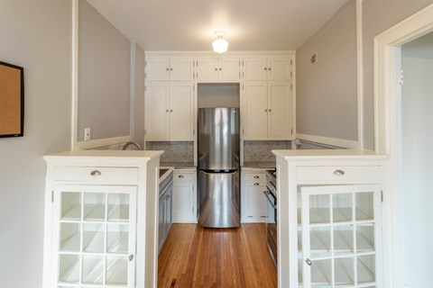 A kitchen with white cabinets and a stainless steel refrigerator.