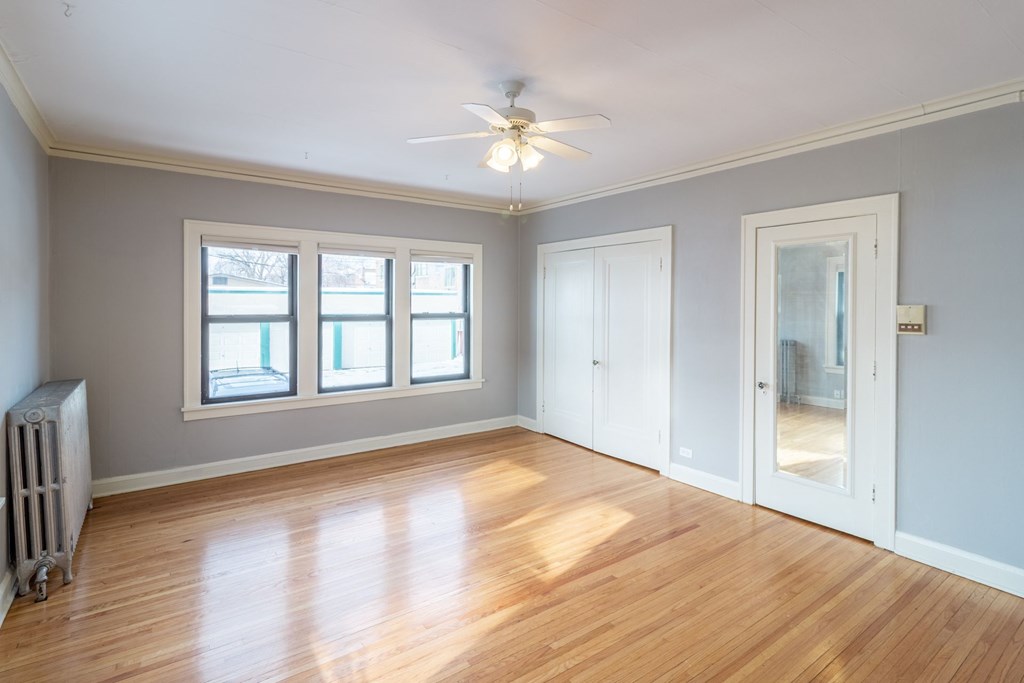 A room with a ceiling fan and wooden floors.
