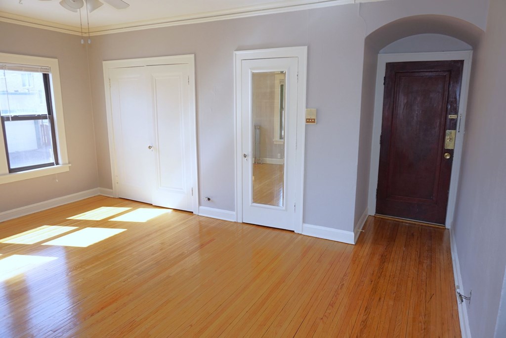 A room with a wooden floor and three doors.