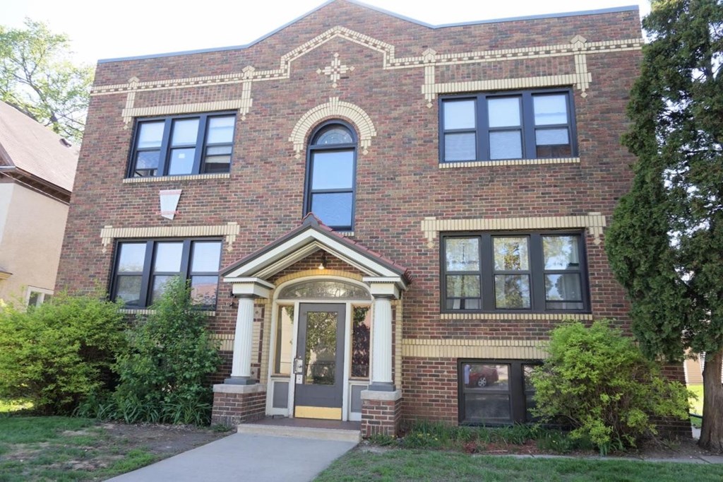 A red brick building with a large arched window and a doorway.