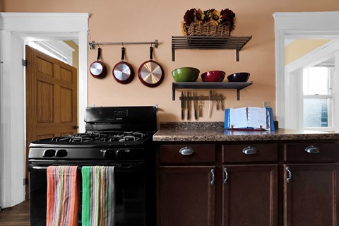 A kitchen with a black stove and wooden cabinets.