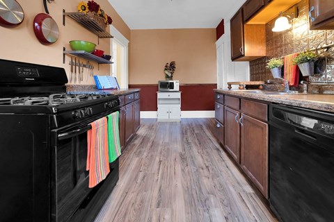 A kitchen with black appliances and wooden floors.