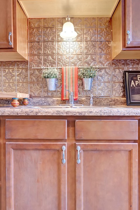 Brown wooden kitchen cabinets with a tile backsplash.