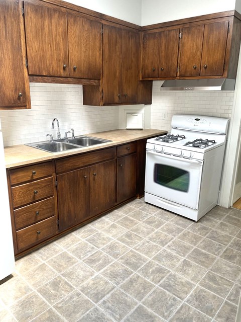 A white stove is in a kitchen with wooden cabinets.