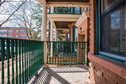 A green fence is in front of a red brick building.