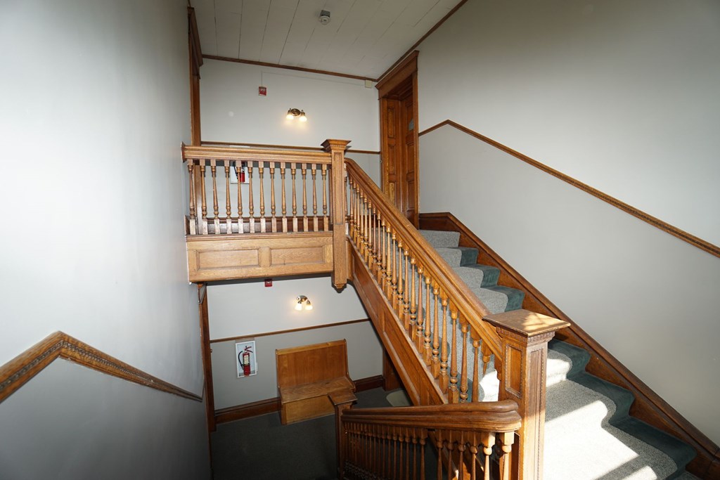 A wooden staircase with a landing and a wall-mounted fire extinguisher.