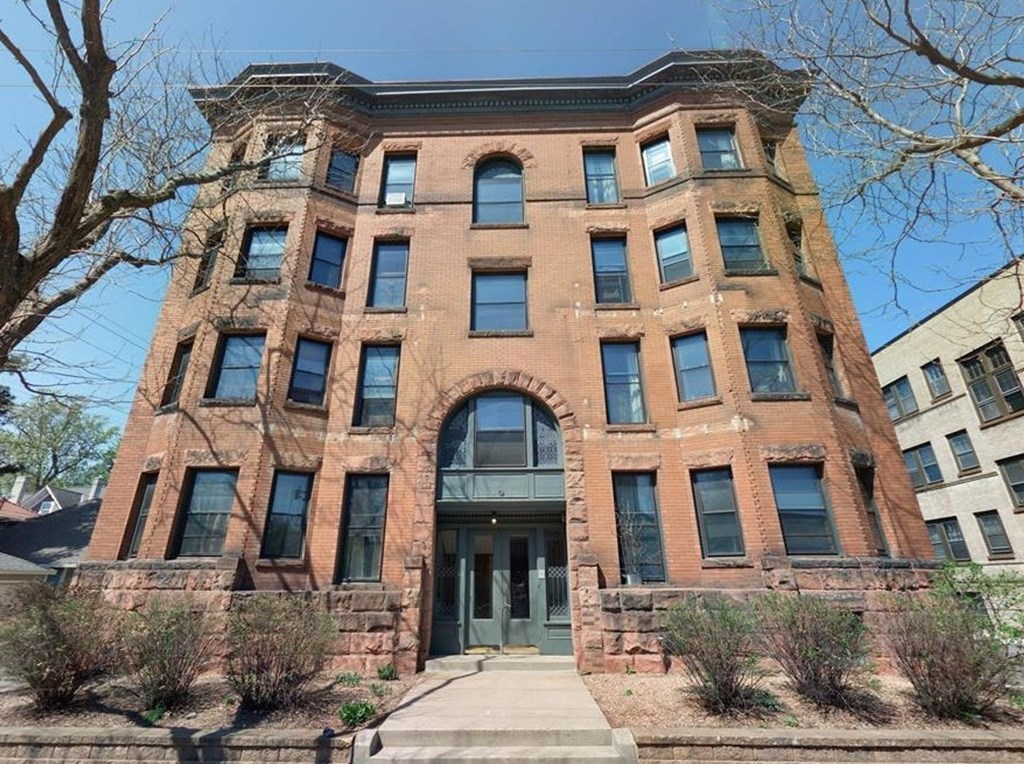 A red brick building with a large arched entrance and a stone wall.