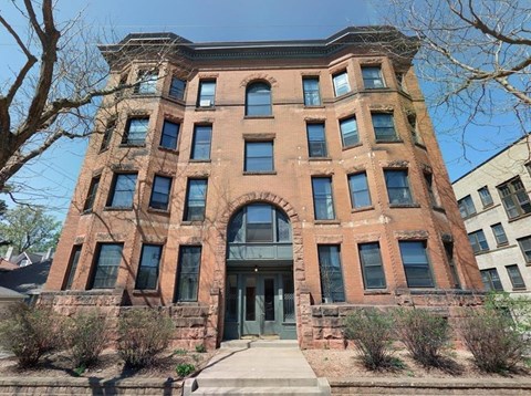 A red brick building with a large arched entrance and a stone wall.