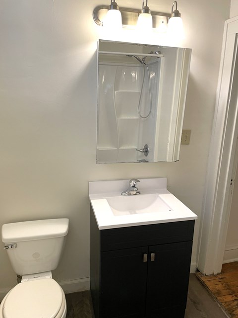 A white toilet sits next to a sink in a small bathroom.
