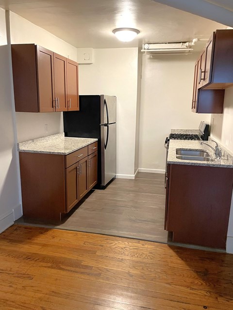 A kitchen with a black fridge and wooden cabinets.