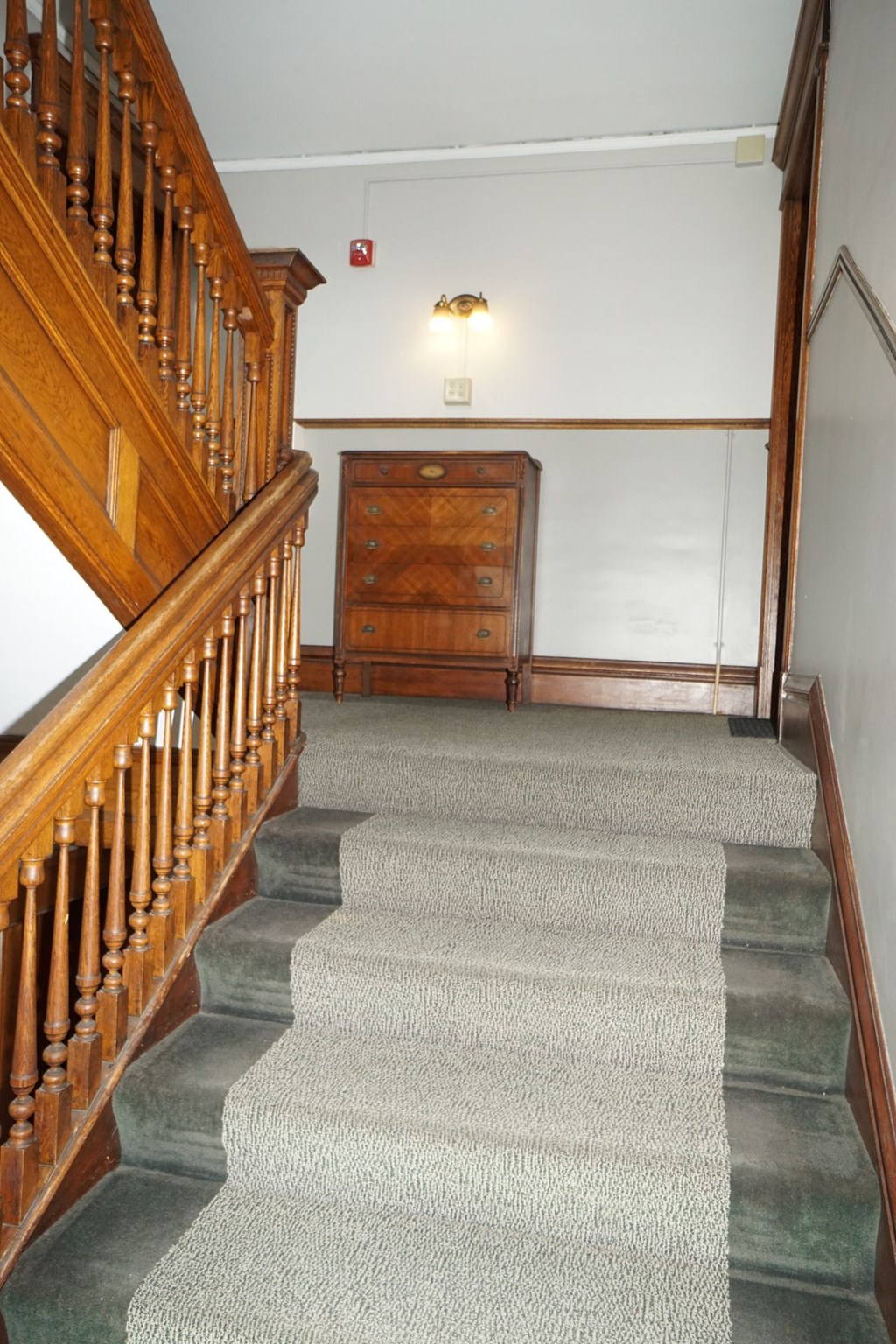 A staircase with a green carpeted runner and wooden balusters.