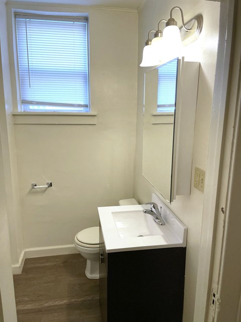 A bathroom with a toilet, sink and mirror.