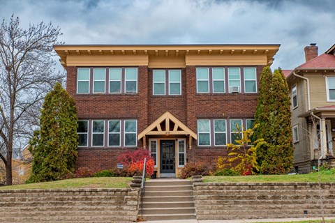 A two-story brick house with a front porch and stairs leading up to the entrance.