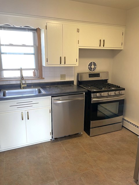 A kitchen with white cabinets and a black stove top oven.