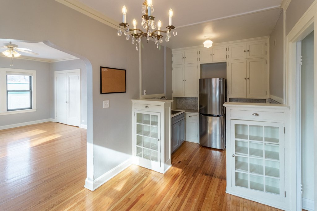 A kitchen with wooden floors and white cabinets.