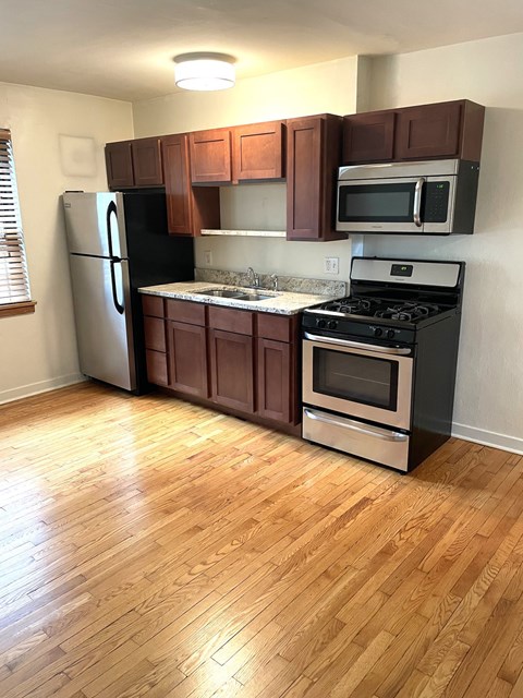 A kitchen with wooden floors and brown cabinets.