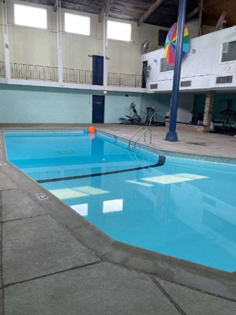 A large indoor swimming pool with a blue tiled edge.