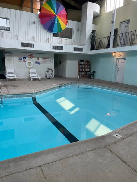 A large indoor swimming pool with a colorful umbrella above it.