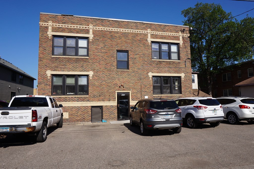 A white pickup truck is parked in front of a brick building.