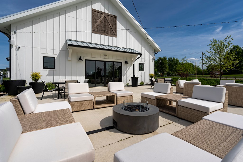 A white patio with a fire pit and chairs.