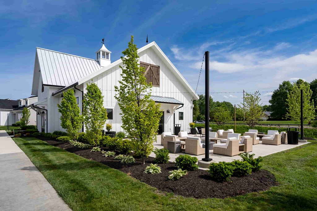 A white building with a black roof and a tree in front.