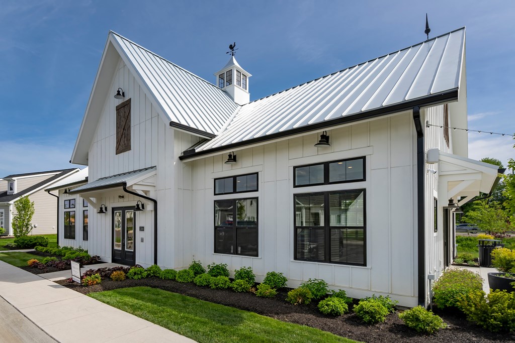 A white house with a black roof and a small tower on top.