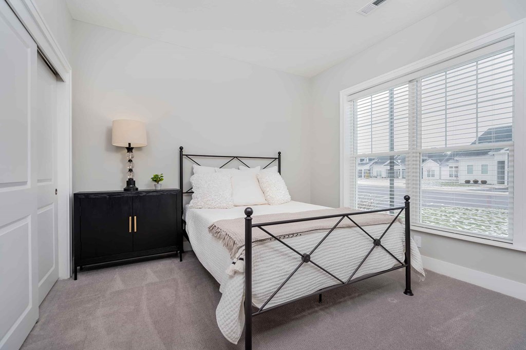 A bedroom with a black metal bed frame and a white bedspread.