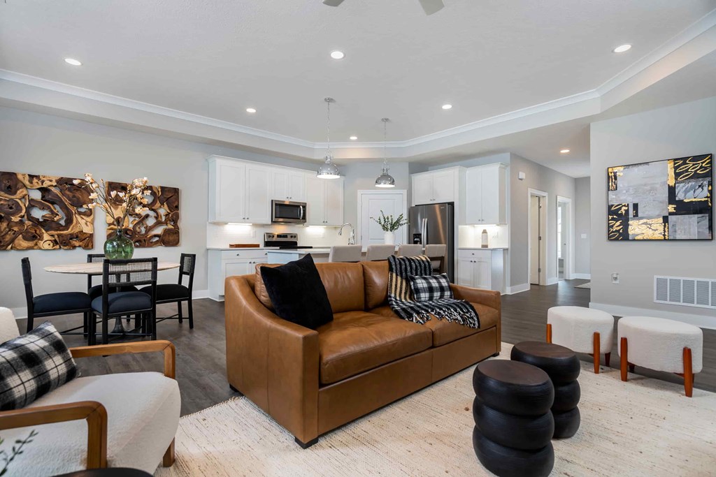 A modern living room with a brown leather couch and a dining table with chairs.