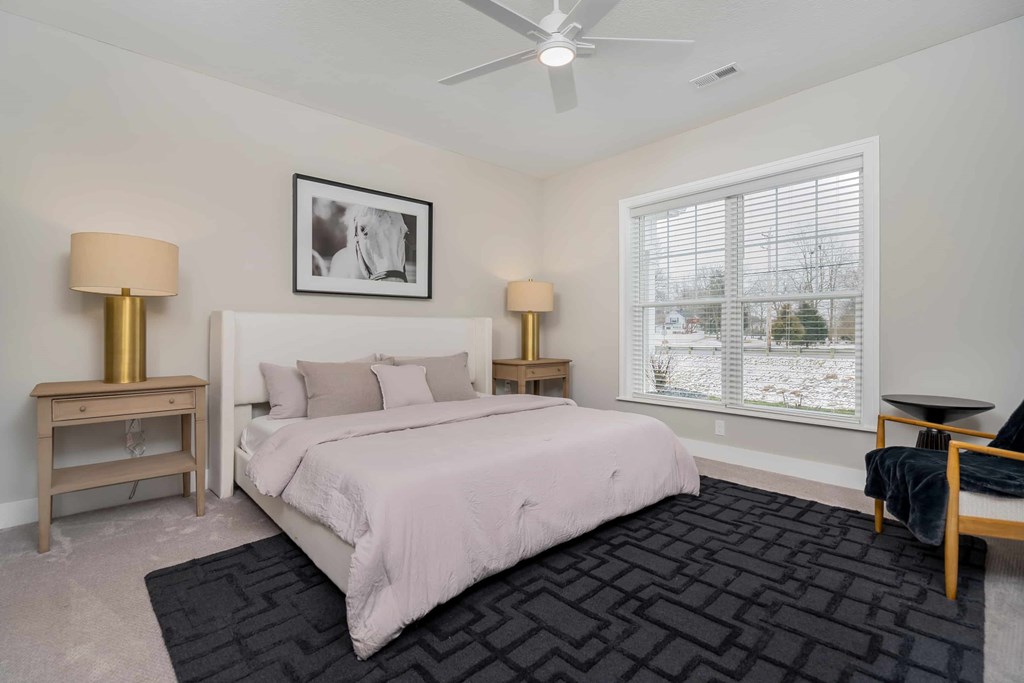 A bedroom with a large bed, two lamps, and a picture on the wall.