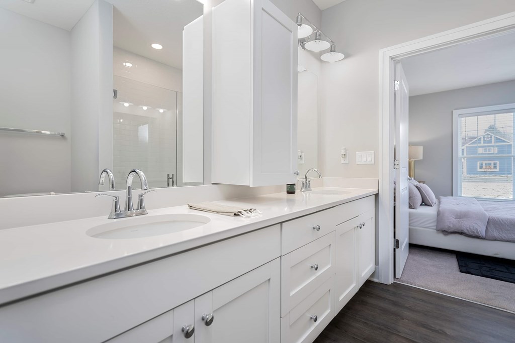 A white bathroom with a double sink and a mirror above it.