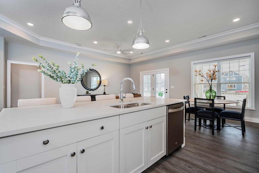 A modern kitchen with white cabinets and a wooden floor.