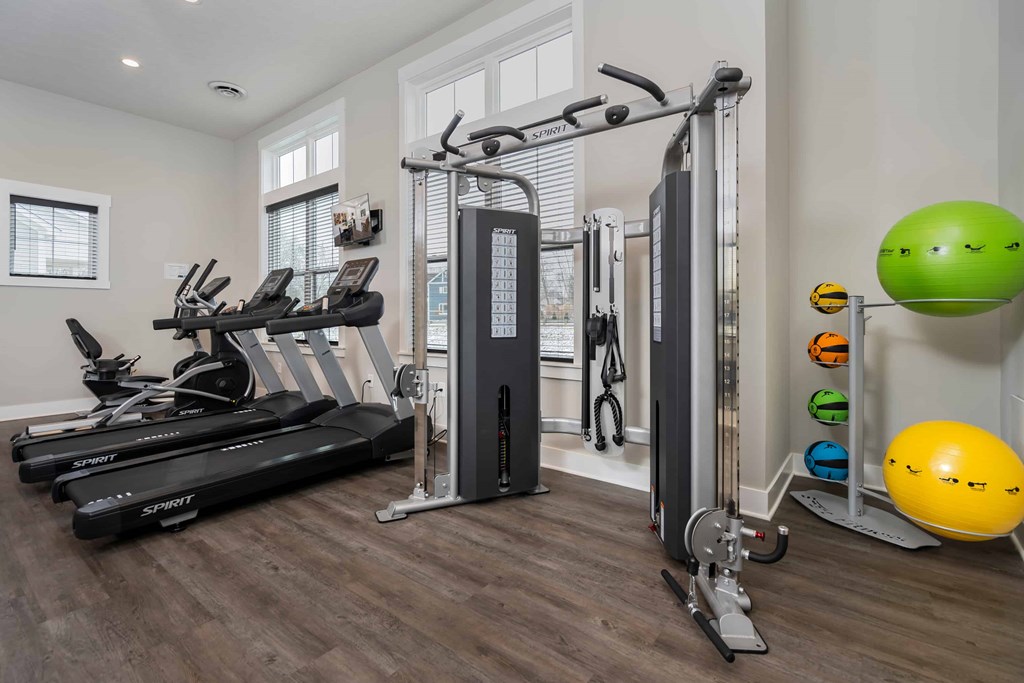 A home gym with a treadmill, a weight machine, and a yellow exercise ball.