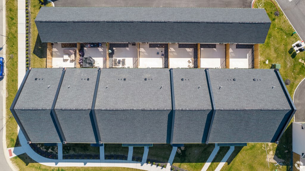 A large building with a grey roof and a white interior is surrounded by a grassy area.