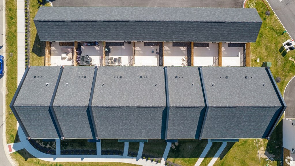 A large building with a grey roof and a parking lot in front.
