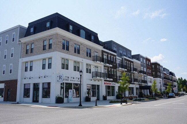 A street view of a row of buildings with the frontmost one having a sign that says "R Fine Dry Goods".