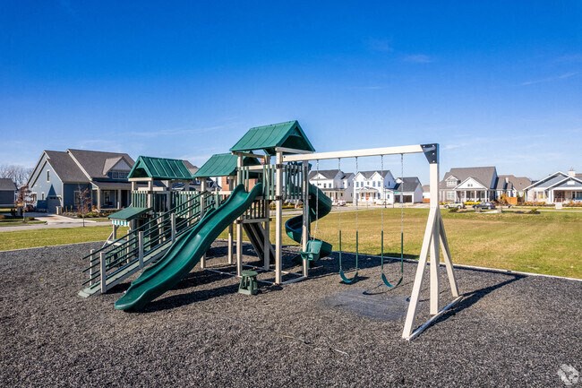 A playground with a green slide and a white swing set.