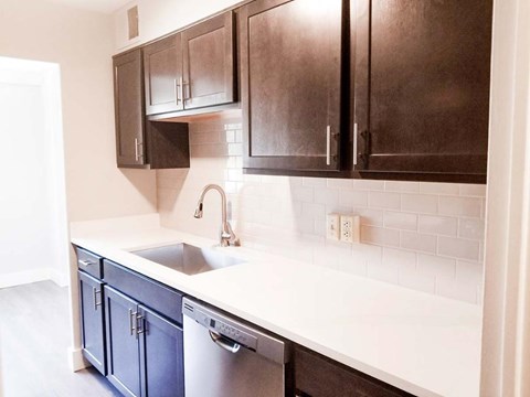 A kitchen with dark brown cabinets and a white counter.