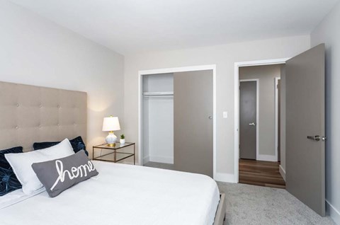 A bedroom with a bed, nightstand, and two doors.