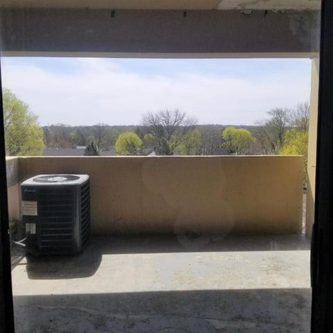 A window with a view of trees and a blue sky.