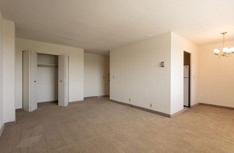 A spacious room with a carpeted floor and a chandelier hanging from the ceiling.