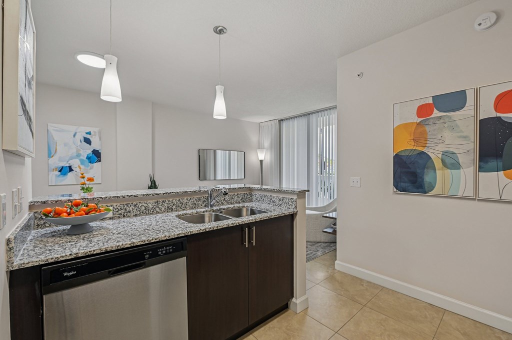 A modern kitchen with a granite countertop and a bowl of fruit on it.